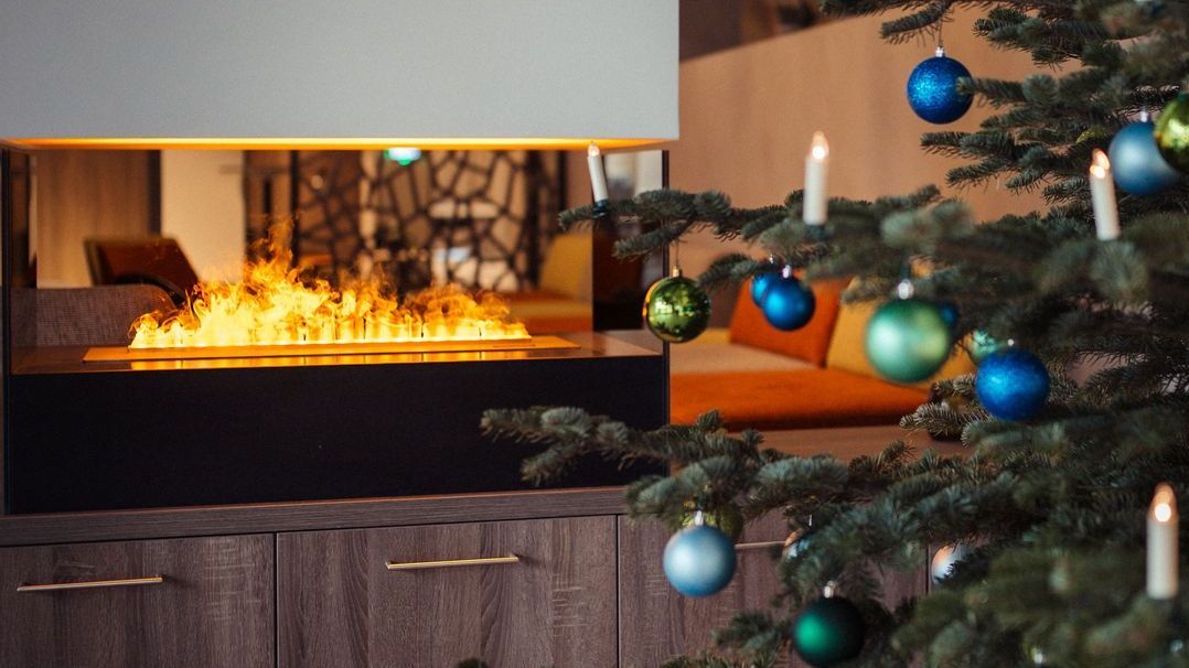 Kaminfeuer hinter einem Weihnachtsbaum in der Hoellobby vom Rainers21